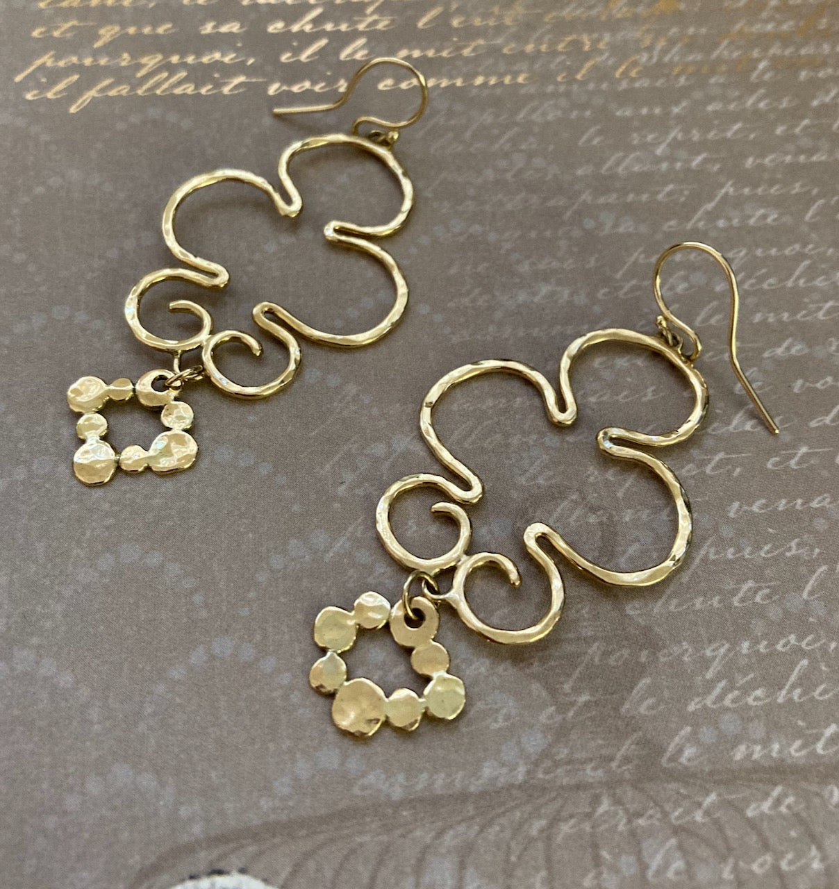 Hammered wire in a bubble-like shape with a smaller, diamond-shaped and also hammered dangle accent hanging below it