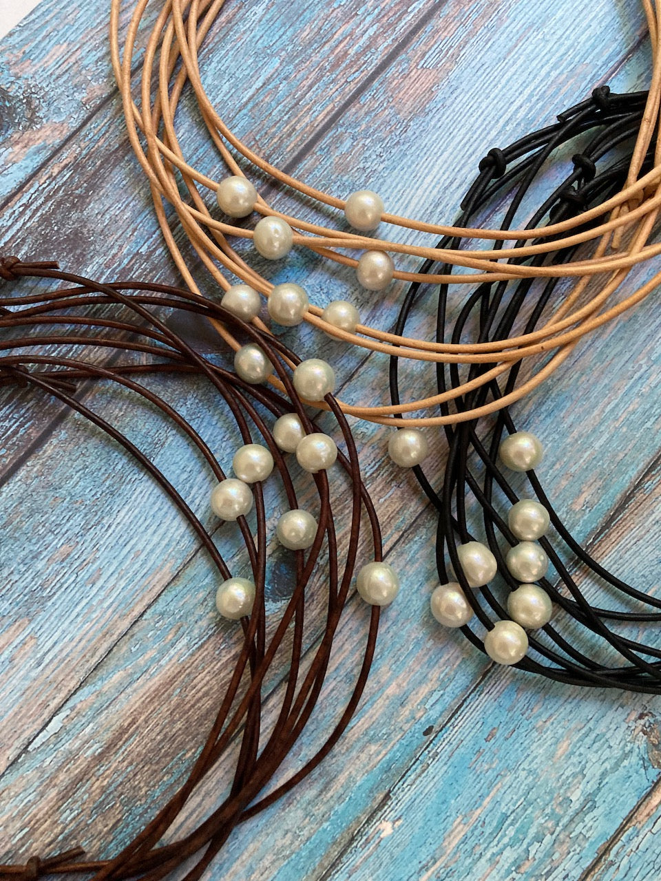 Three groups of freshwater pearls on leather cords. Brown, natural and black.
